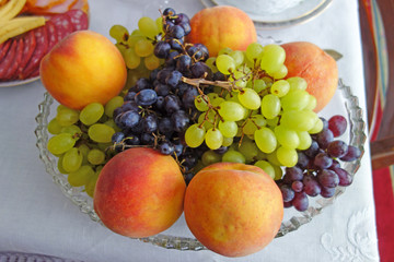 Glass vase with peaches and grapes