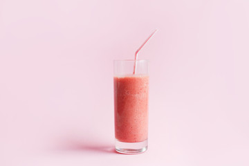 Strawberry smoothie or milkshake in glass on pink pastel background