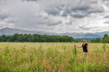 Caucasian woman walking in a green meadow in the Great Smoky Mountains on a cloudy day
