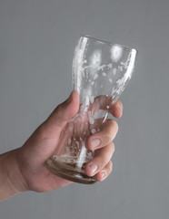 Hand holding empty beer glass on gray background