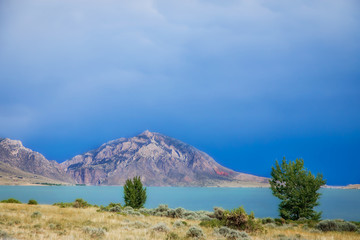 The Shoshone River backed by mountains under a blue overcast sky in a summertime Wyoming landscape