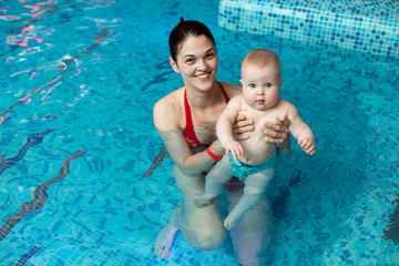 baby with mom learns to swim in the pool