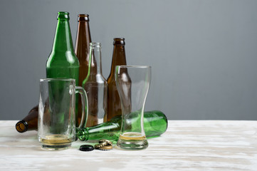 Empty beer glass with bottle caps and bottles on table wood,after party