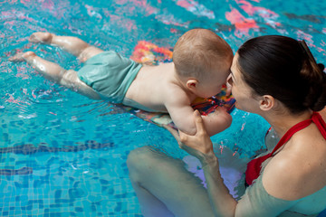 baby with mom learns to swim in the pool