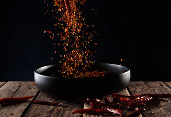 Pouring cayenne pepper powder into the bowl on wood table,Motion blur