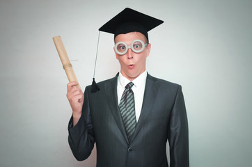 Delighted graduate student in the cap with diploma certificate isolated on gray background. Education concept.