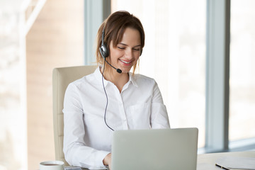 Smiling telemarketer, customer service operator or manager wearing headset consulting client making...