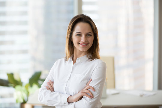 Smiling confident businesswoman looking at camera in office, happy young female ceo, secretary or successful business owner portrait, successful entrepreneur or young professional manager headshot