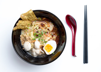 Thai spicy noodle,Thai yellow noodle tom yum with pork,egg and meat ball isolated on white