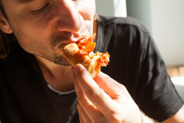 A man with a pleasure eating pizza