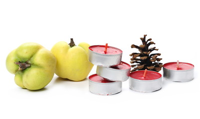 Tea light candles in aluminum candle holders, fir cone, and quince isolated on white background