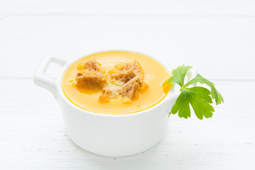 Vegetarian pumpkin soup with dry bread nd parsley in white bowl