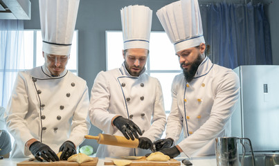 Three chefs at the restaurant make pies with cabbage © razoomanetu