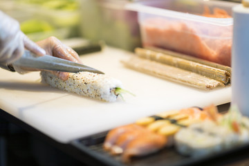 Sushi preparation in japanese restaurant, close up on chief hands cutting roll