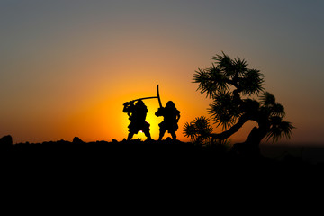 Silhouette of two samurais in duel. Picture with two samurais and sunset sky. Selective focus