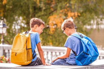 Two boys after school, sitting on bench and talking