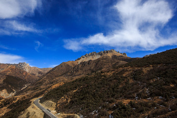 Mountain scenery on the road between Shangri-La and Deqin, Yunnan Province China. High altitude mountains, snow and alpine forests. Dirt/Rocks, cliffs and rocky summits. Fresh air, bright blue sky
