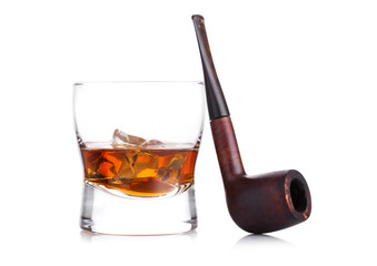 Glass of whiskey with ice cubes and vintage smoking pipe on white background. Cognac brandy drink