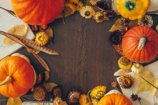 Thanksgiving background with autumn dried flowers, pumpkins and fall leaves on the old wooden background. Abundant harvest concept