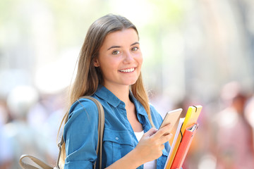 Happy student posing with a phone in the street