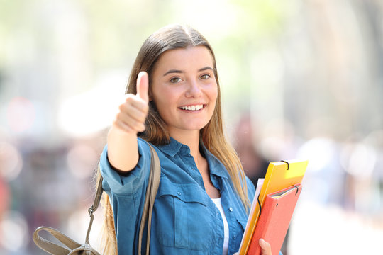 Happy student in the street with thumb up