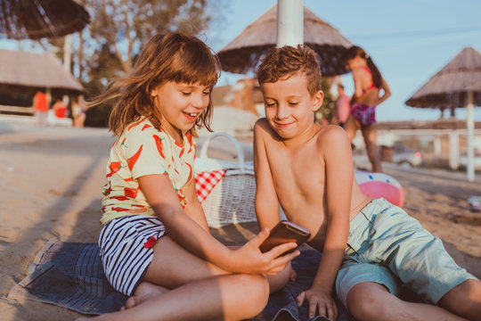 Children using mobile phones on sandy beach