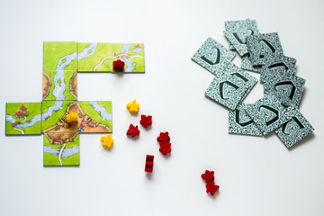 Close up red and yellow meeples in hand isolated on white background. Components of board games. Small figures of people's body in hand. Vacation time. Gameplay.