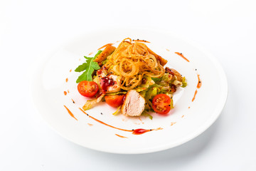 Chicken salad with tomatoes, arugula and French onions white plate. Close-up