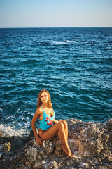 Young sexy woman with tanned skin in a swimsuit near the sea