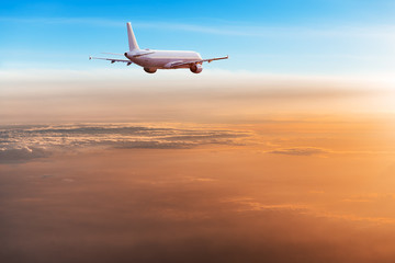 Commercial airplane flying above dramatic clouds.