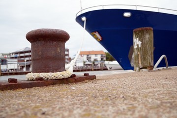 Fototapeta premium Rusty bollard with rope and boat at the pier
