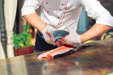 The chef cuts the salmon on the table.