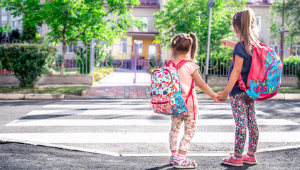 Children go to school, happy students with school backpacks and holding hands together