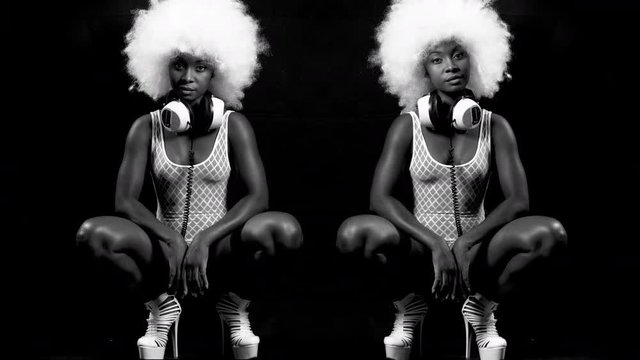 beautiful african female model in large afro wig posing crouched in white lingerie and headphones.