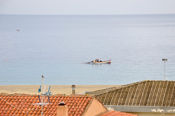 Sandy beach of the Ionian Sea, South Italy city of Bova Marina, fishermen on a boat fishing .