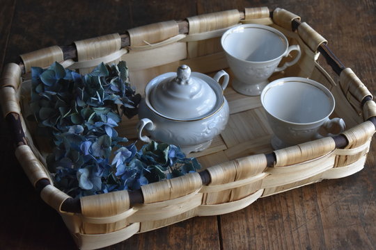 cesta hecha a mano, tazas y azucarero vintage, flores de hortensia 