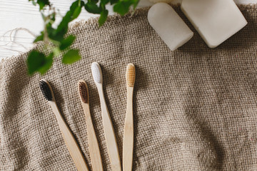 eco natural bamboo toothbrushes on rustic background with greenery. sustainable lifestyle concept. zero waste flat lay. bathroom essentials, plastic free items