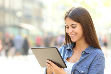 Happy teen uses a tablet in the street