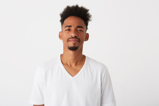 Portrait of serious confident african american young man with curly hair wears t shirt looks pensive and thinking isolated over white background