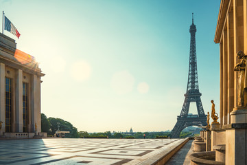 Paris street with view on the famous paris eiffel tower on a sunny day with some sunshine - obrazy, fototapety, plakaty