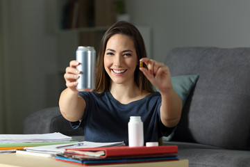 Happy student showing energy drink and vitamin pill