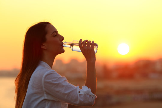 Healthy girl drinking water at sunset