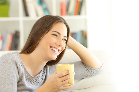 Happy woman thinking looking at side at home