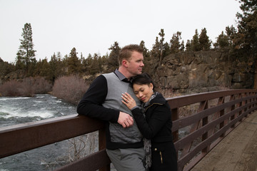 Fototapeta premium Newly weds loving and holding each other close on a bridge by a river