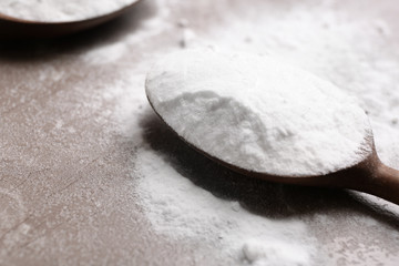 Spoon with baking soda on table, closeup