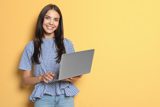 Young woman with modern laptop on color background