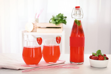 Bottle and glasses with natural lemonade on table indoors