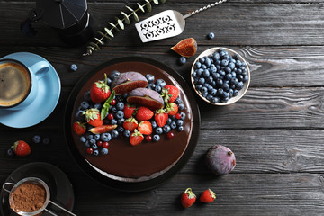 Fresh delicious homemade chocolate cake with berries on dark table, flat lay