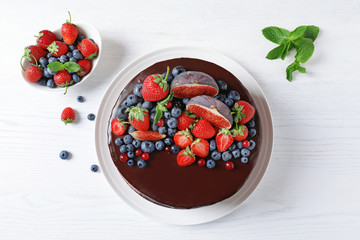 Fresh delicious homemade chocolate cake with berries on light table, flat lay