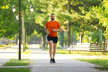 Young man running in park on sunny day